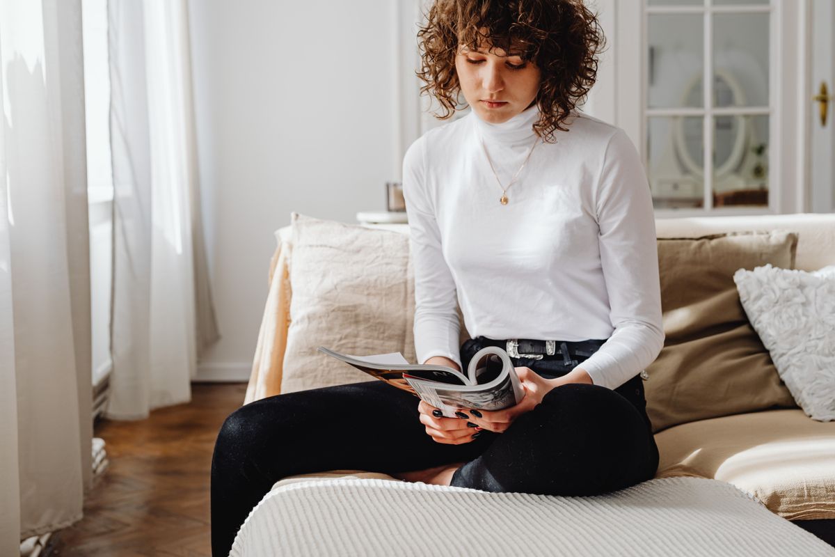 Une femme lisant un magazine dans son salon
